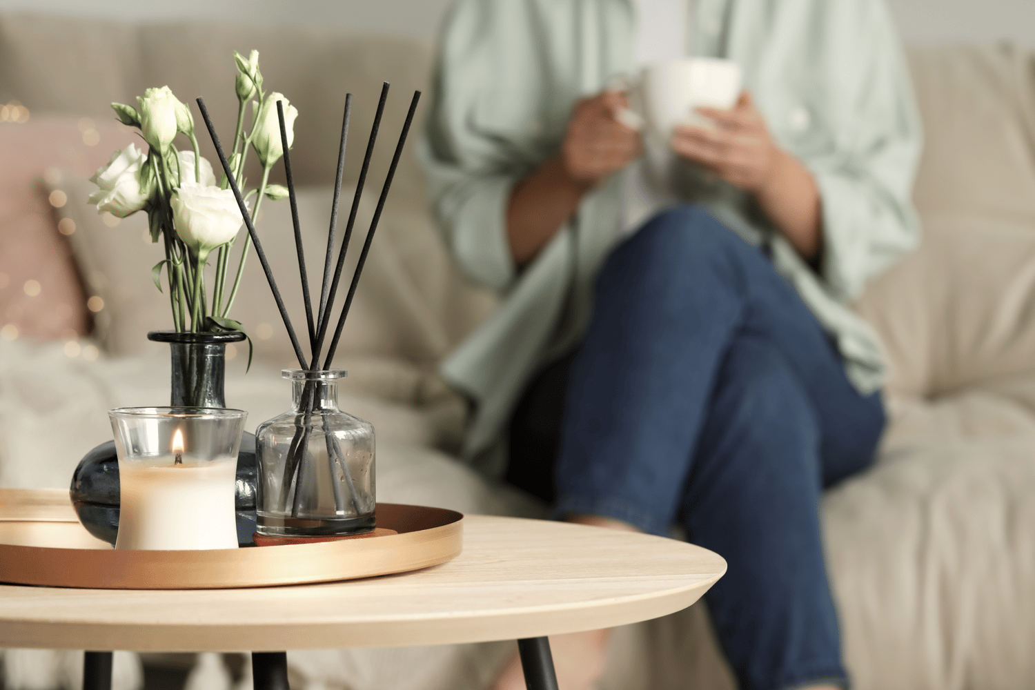 a woman sitting on the couch of a pretty apartment drinking coffee