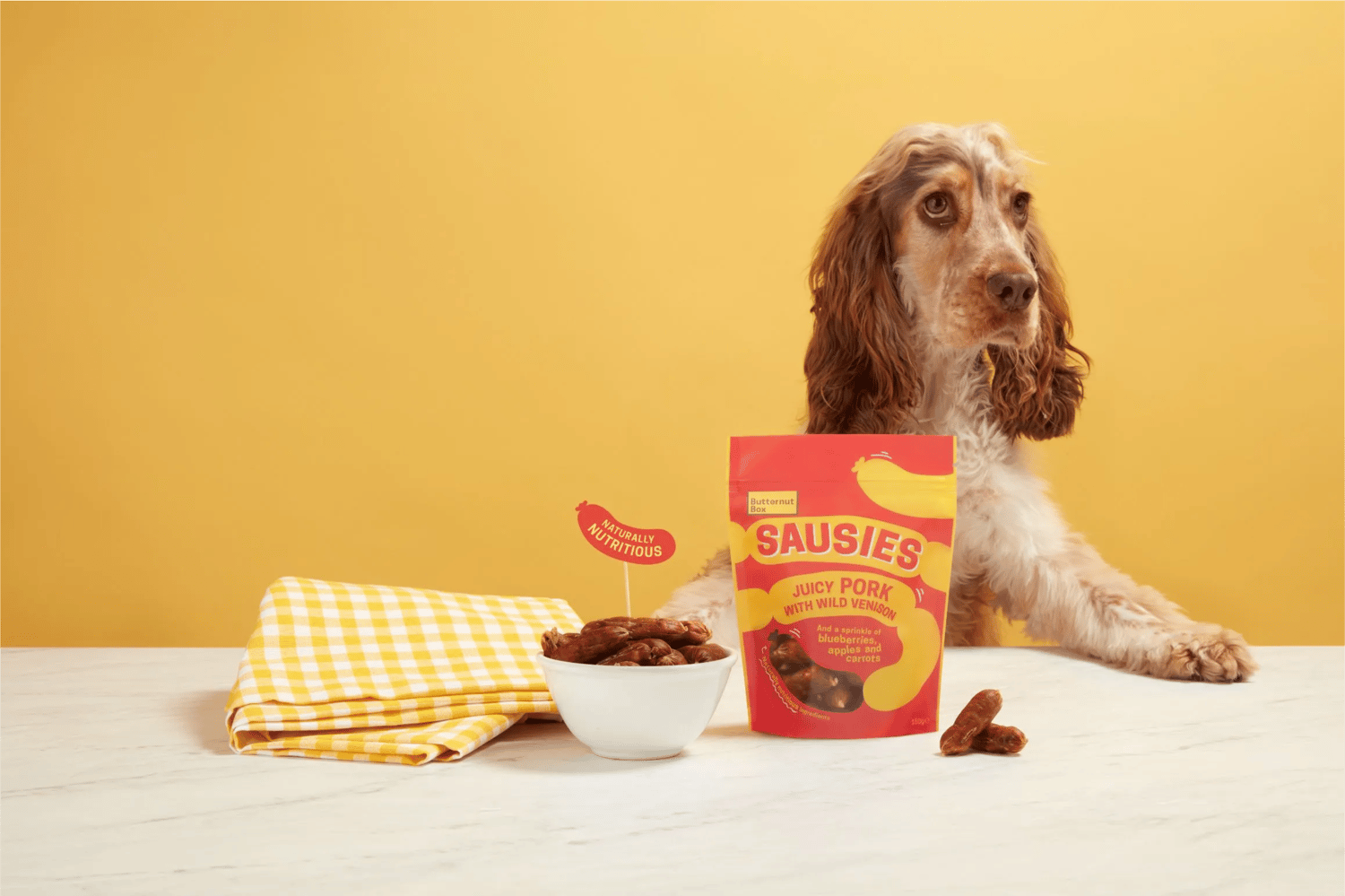 a dog standing against a table looking at dog food
